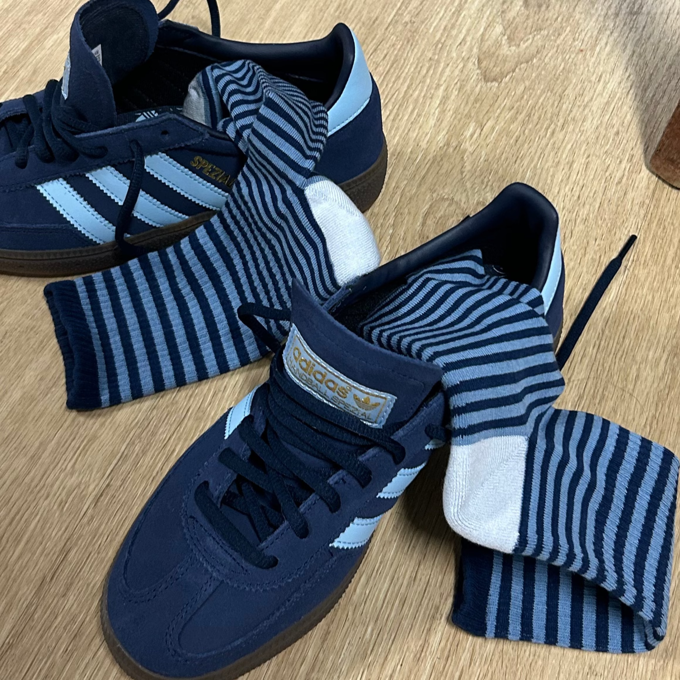 Pair of blue socls with white stripes on a wooden floor.