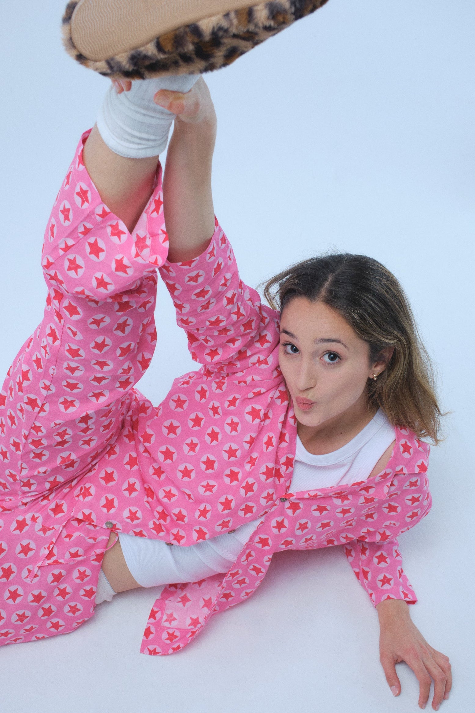 Person wearing a pink floral outfit with a leopard print object above them on a white background