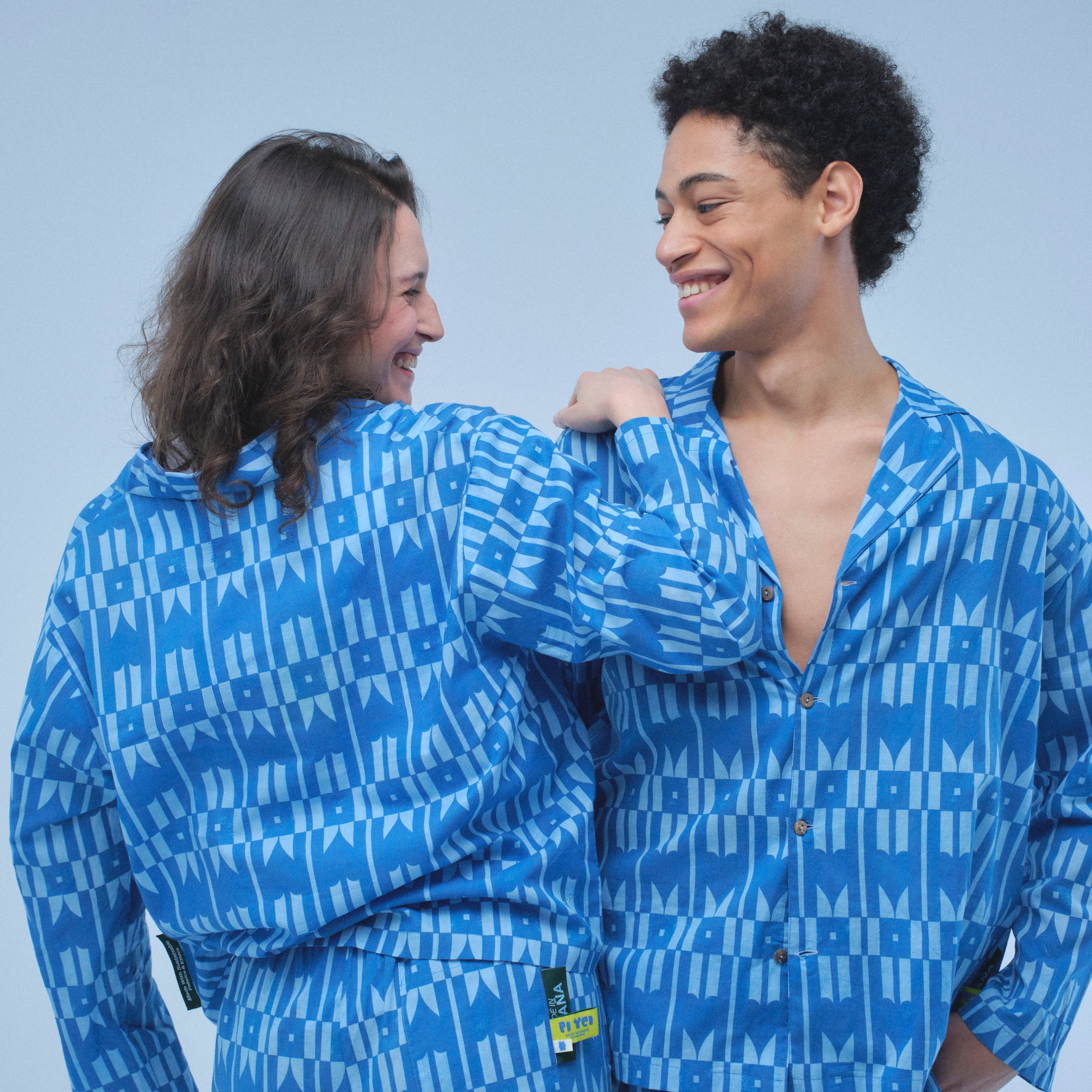 Two people wearing matching blue pajama sets against a light gray background